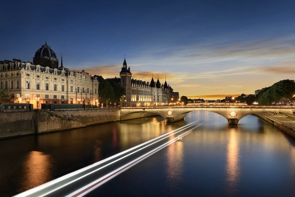 Consiergerie, Pont Neuf and Seine river with tour boat at sunny summer sunset, Paris, France