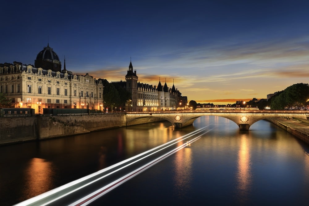 Consiergerie, Pont Neuf and Seine river with tour boat at sunny summer sunset, Paris, France